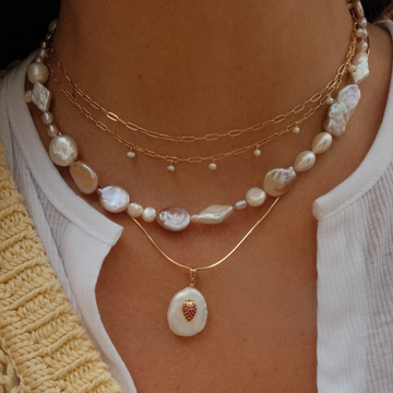 Peson wearing multiple different styles of pearl necklaces 