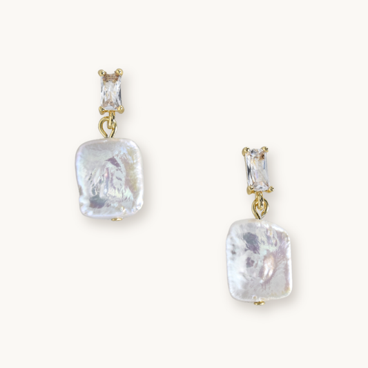 Elegant earrings featuring rectangular gemstones above irregularly shaped, lustrous pearl drops, all set in gold. Sophisticated and stylish.