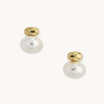 Gold earrings with round white pearls, reflecting light. Simple and elegant design on a plain white background, conveying a sense of sophistication.