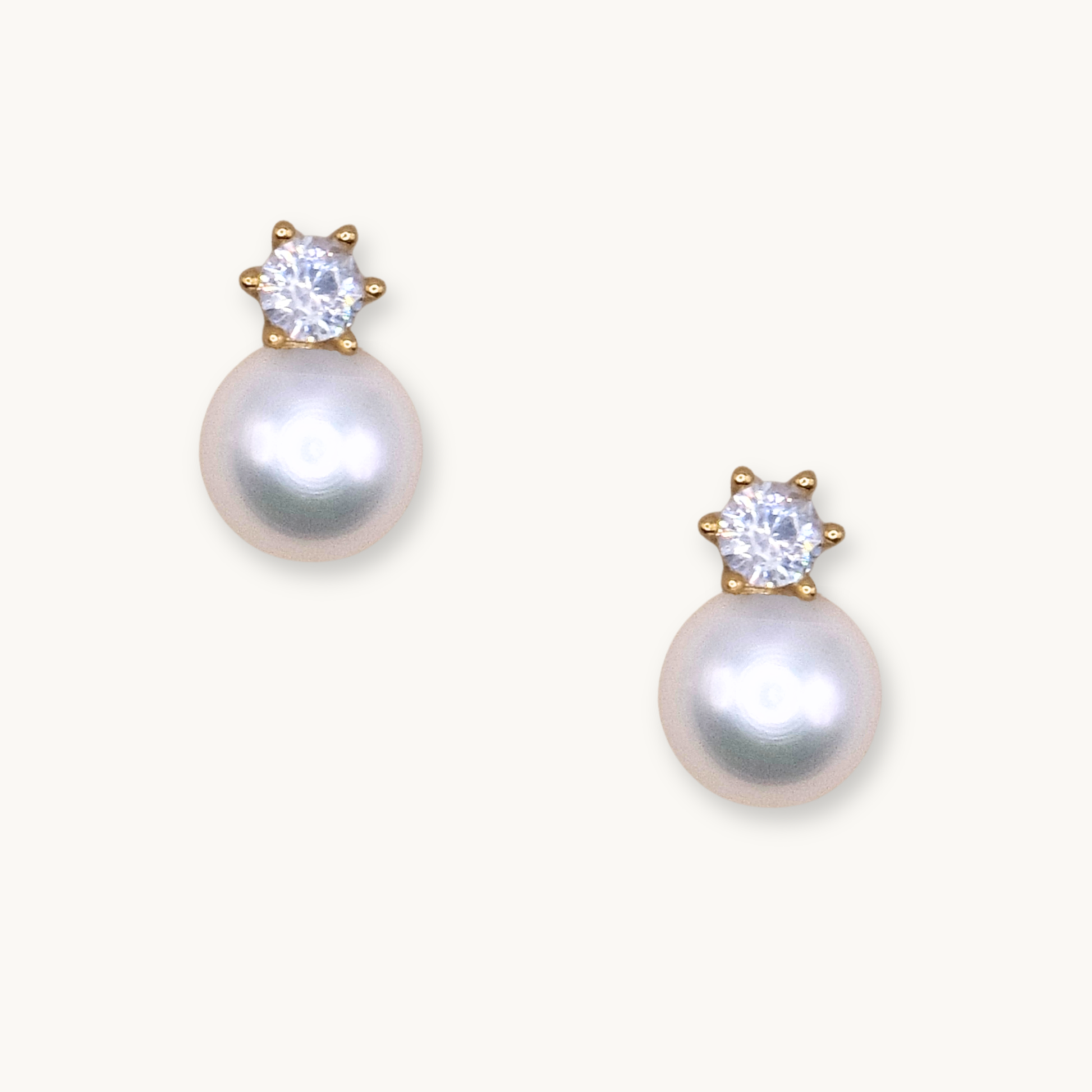 Elegant pearl earrings with sparkling gemstones set in gold. The pearls exude a soft, classic beauty, while the gems add a touch of glamour.