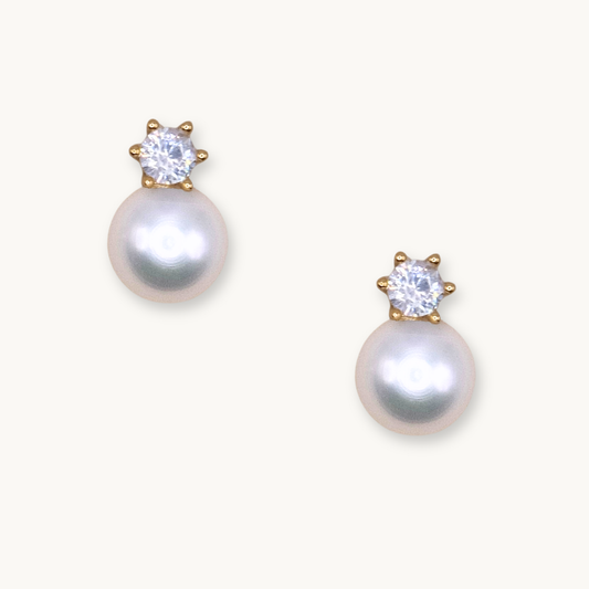 Elegant pearl earrings with sparkling gemstones set in gold. The pearls exude a soft, classic beauty, while the gems add a touch of glamour.