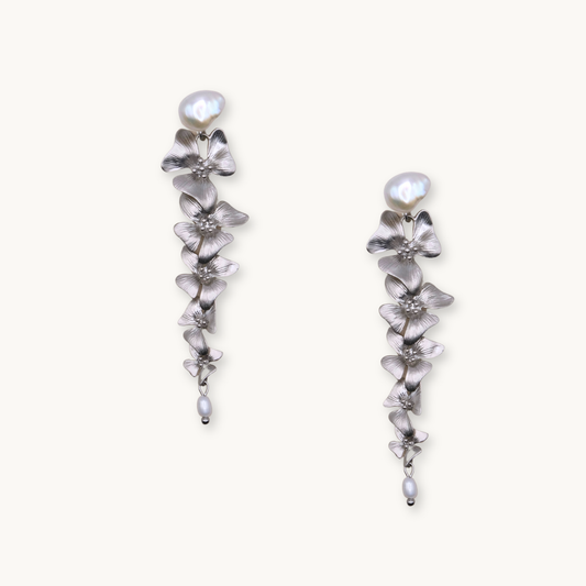 Silver floral drop earrings with cascading flower design, topped with large pearls. Elegant and delicate, conveying a sense of sophistication.