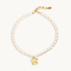 A delicate necklace featuring a strand of small white pearls and a central gold flower charm. It has an adjustable golden clasp. Elegant design.