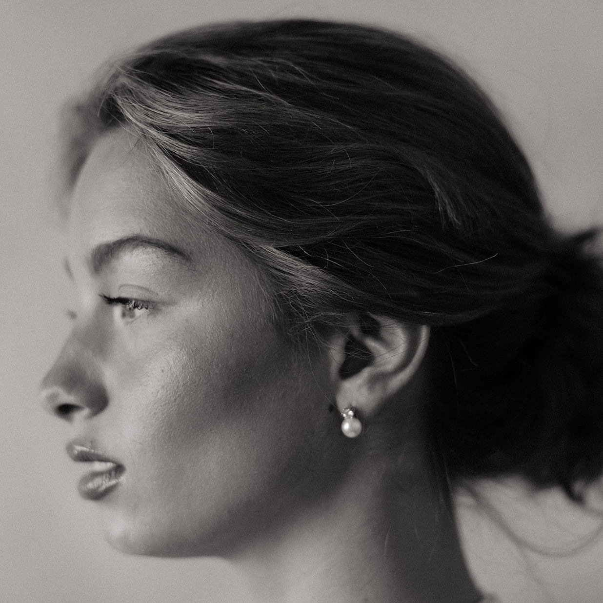 Black and white portrait of a woman with minimal makeup and jewelry.