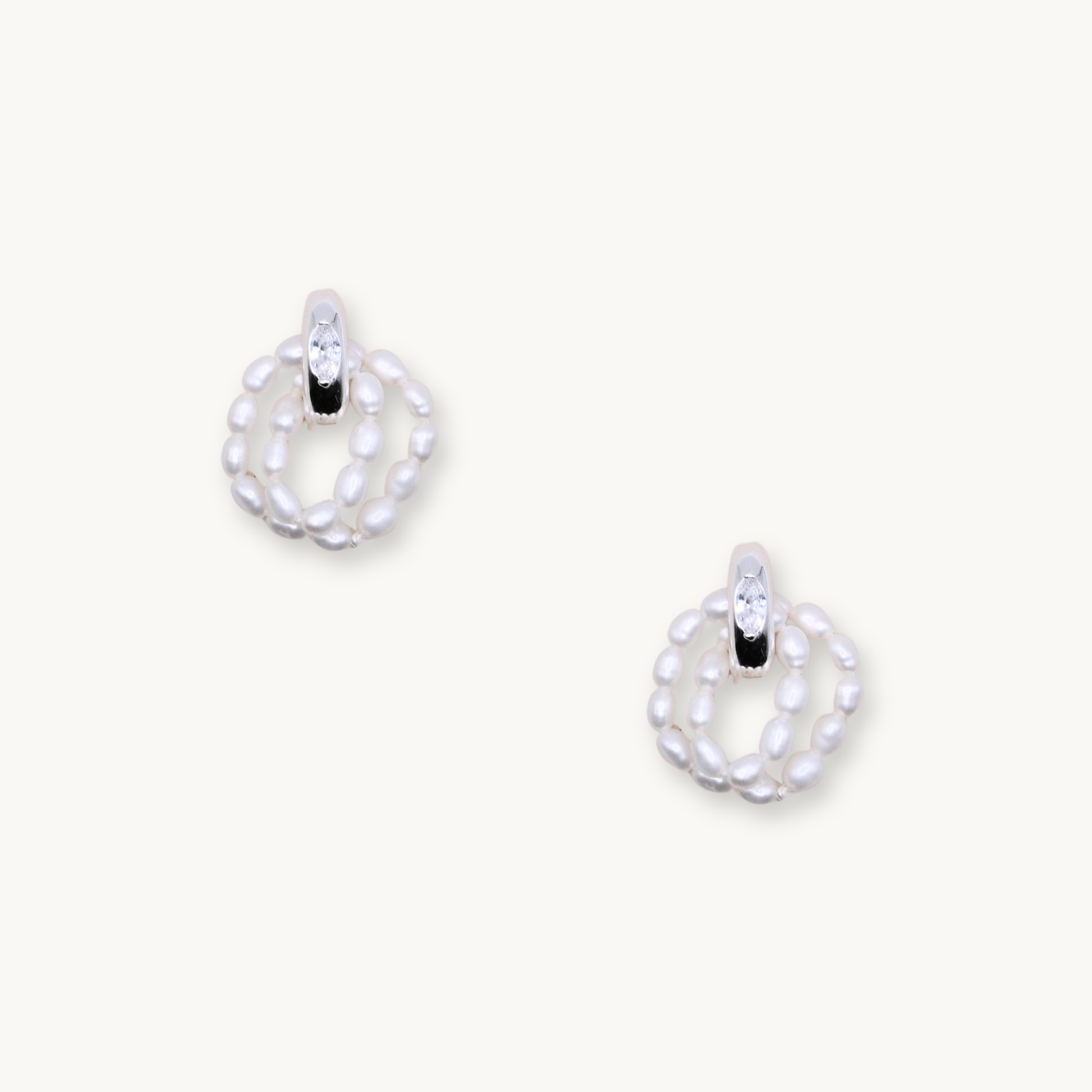Elegant earrings featuring a loop of small white pearls with a sparkling crystal accent at the top. Set against a light background, they convey sophistication.