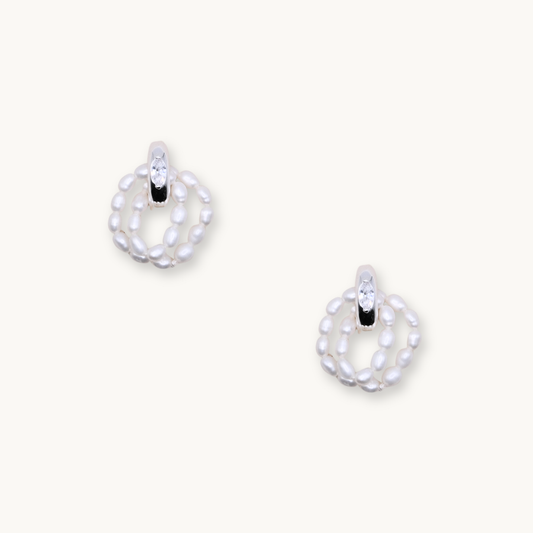 Elegant earrings featuring a loop of small white pearls with a sparkling crystal accent at the top. Set against a light background, they convey sophistication.
