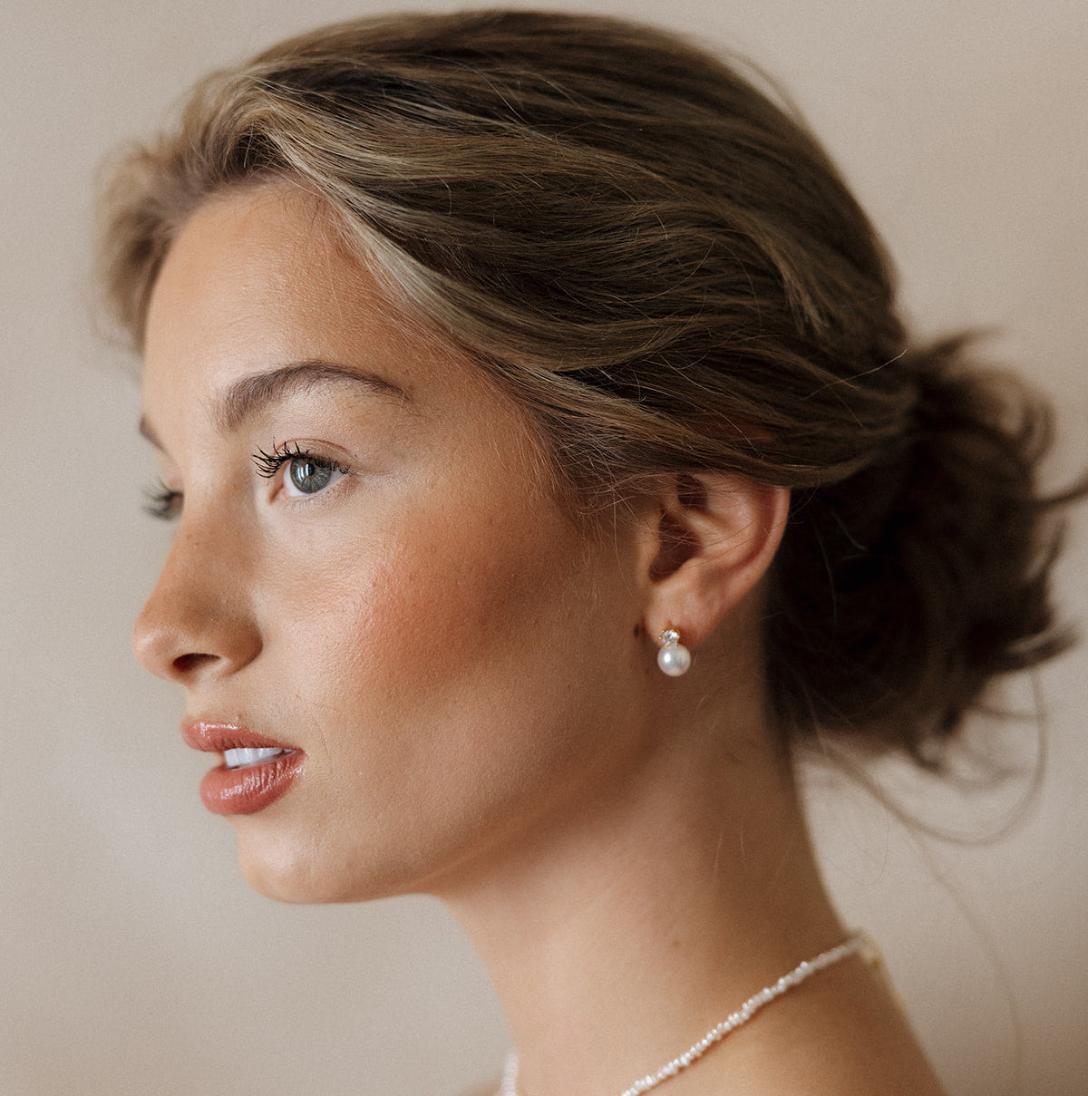 Woman wearing a delicate necklace and earring set against a neutral background