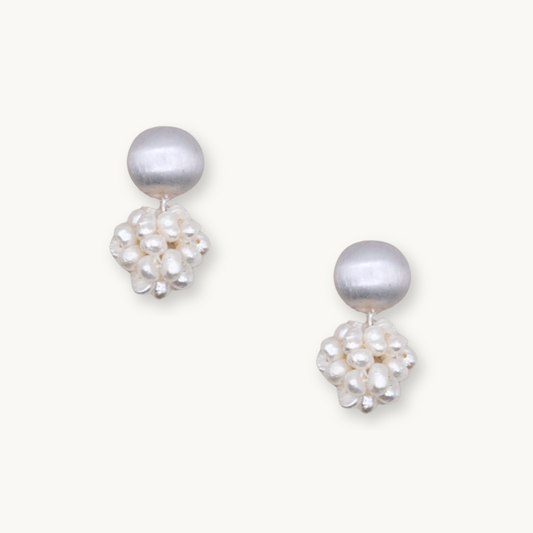 Elegant pearl earrings featuring a smooth, round white pearl atop a cluster of smaller, irregular pearls on a light background.