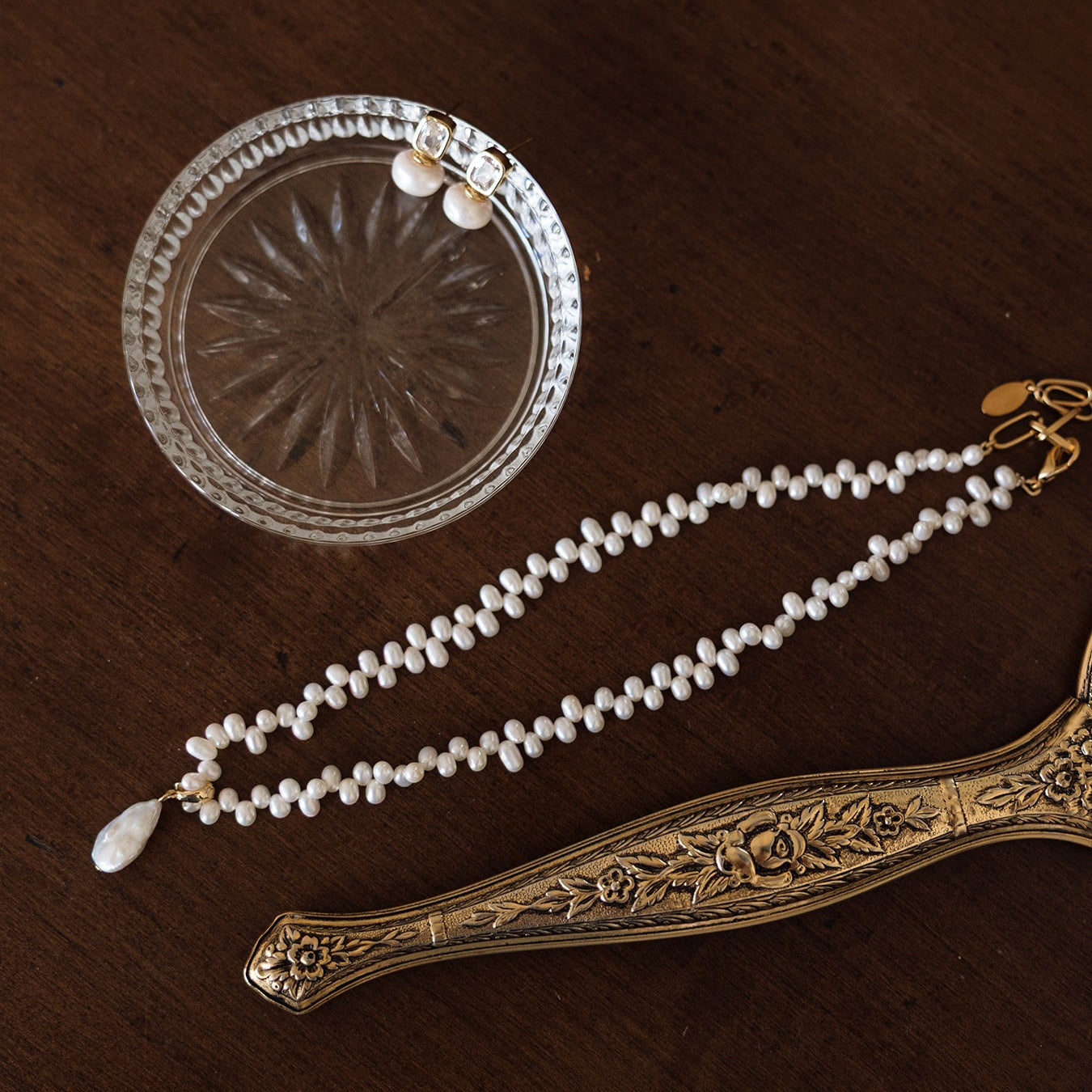 Pearl necklace with decorative clasp on a brown textured surface