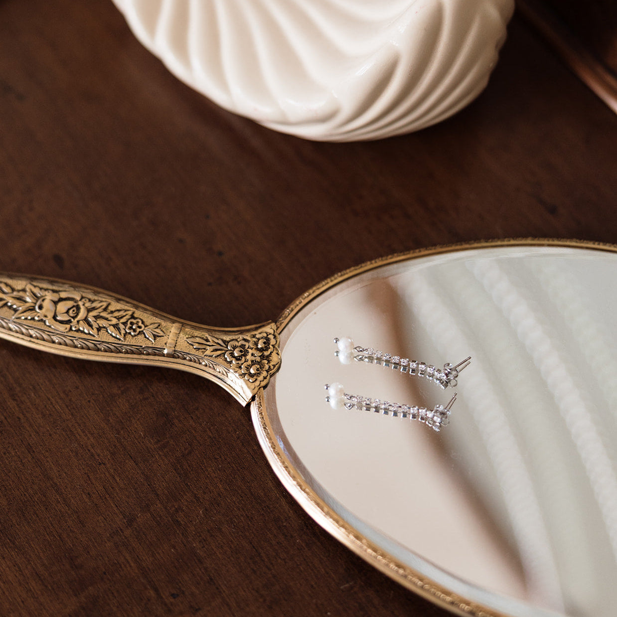Decorative hand mirror with intricate gold handle on a wooden surface