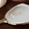 Pearl earrings on a decorative hand mirror with a wooden background