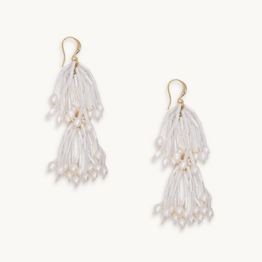 Elegant white pearl tassel earrings with gold hooks, featuring cascading beads and pearls. They exude a delicate and sophisticated charm.