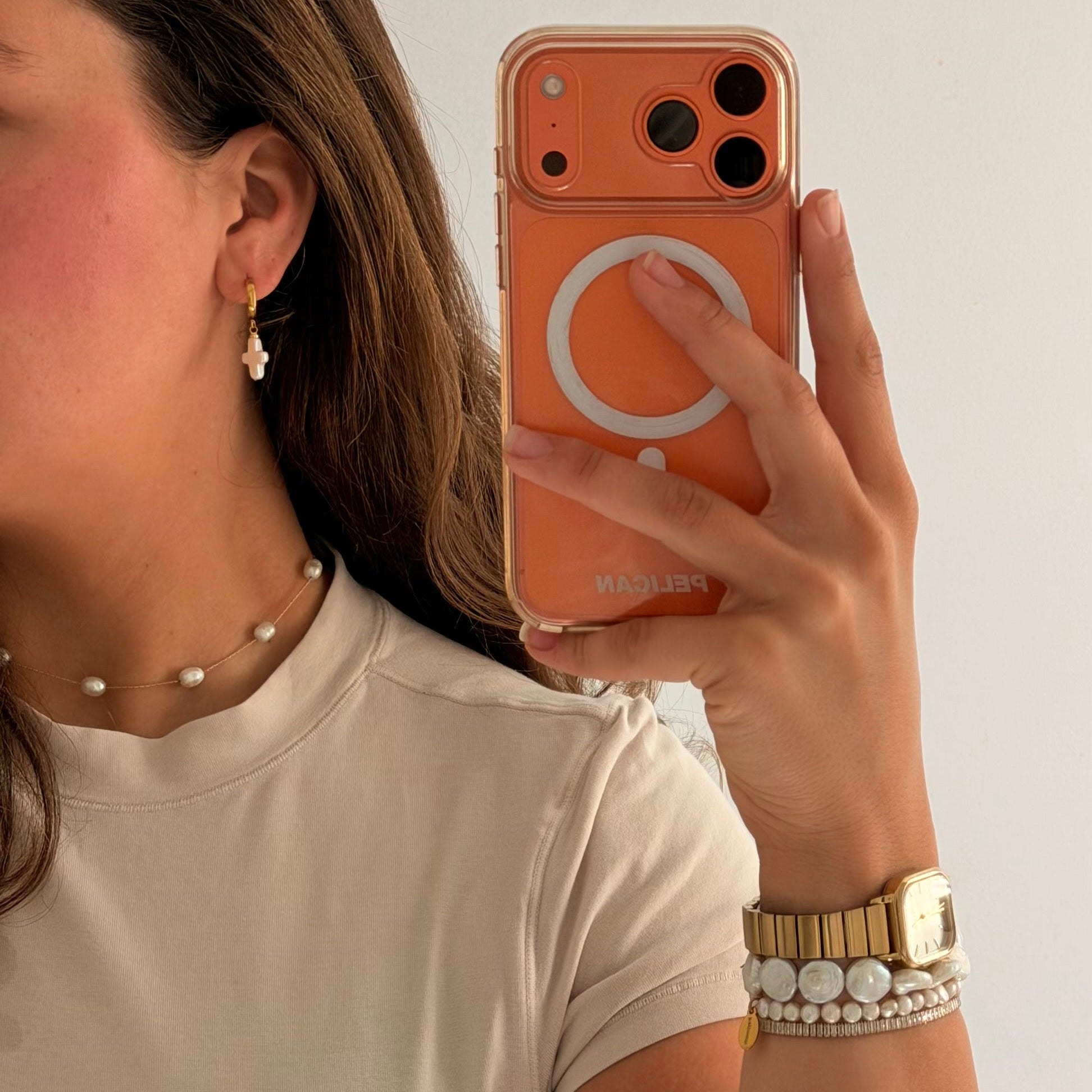 Lady wearing dainty cross pearl earrings with delicate strand pearl necklace 