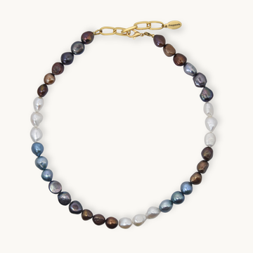 A baroque pearl necklace with a gold clasp, featuring a gradient of pearl colors from white and light blue at the front, through gray and brown, to deep purple at the back. 