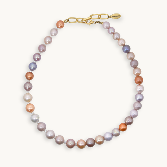 Pink, purple, and orange toned pearls on a necklace with gold hardware. 