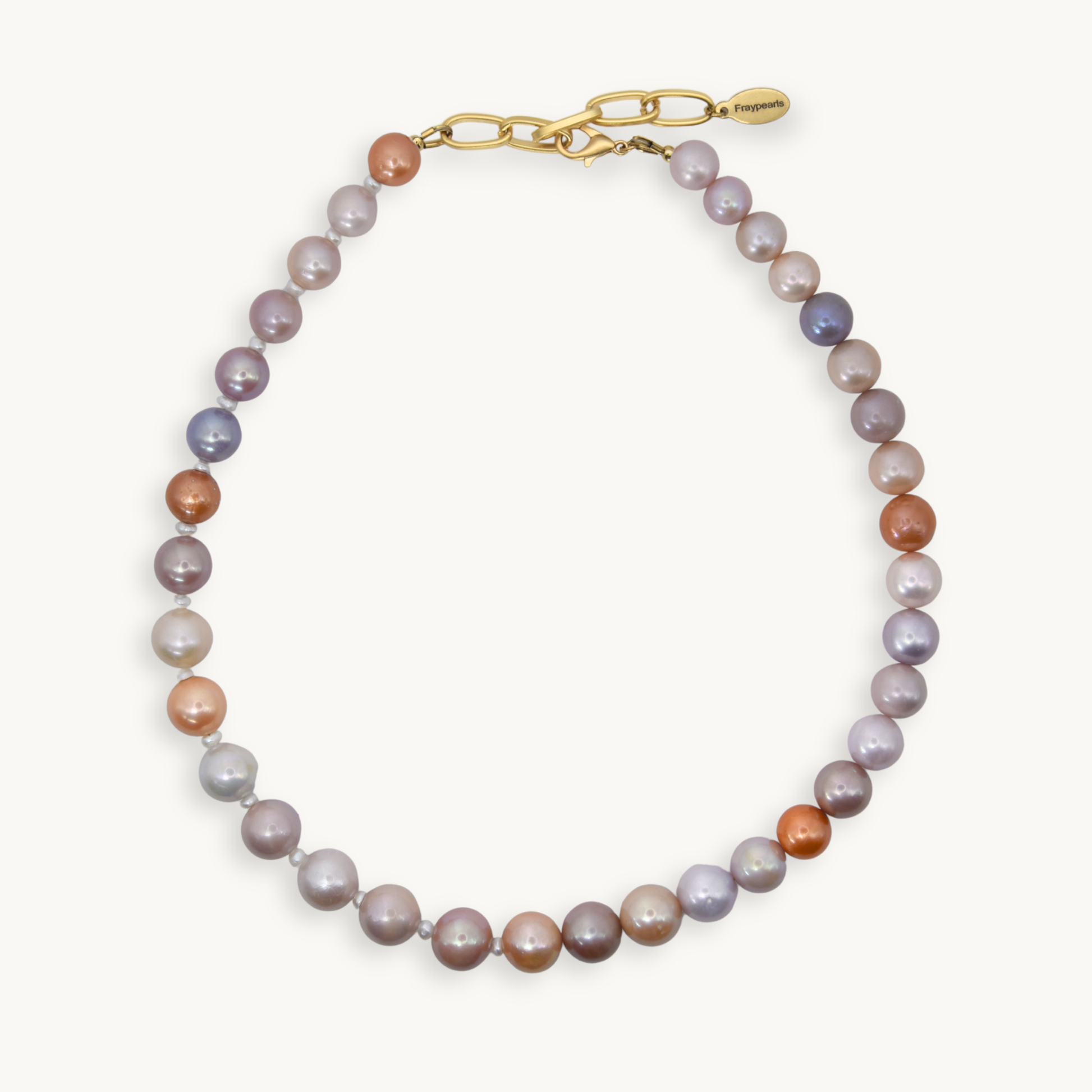 A necklace made of freshwater pearls in shades of lavender, gray, peach, and bronze, finished with a gold clasp and extender chain.