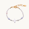 A delicate bracelet featuring an asymmetrical mix of white, pink, and purple pearls, with a central irregular pearl, and a gold chain clasp. Elegant and sophisticated design.