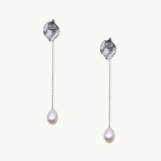 Silver drop earrings with textured petal-like tops and delicate chains ending in teardrop-shaped pearls, conveying elegance and simplicity.