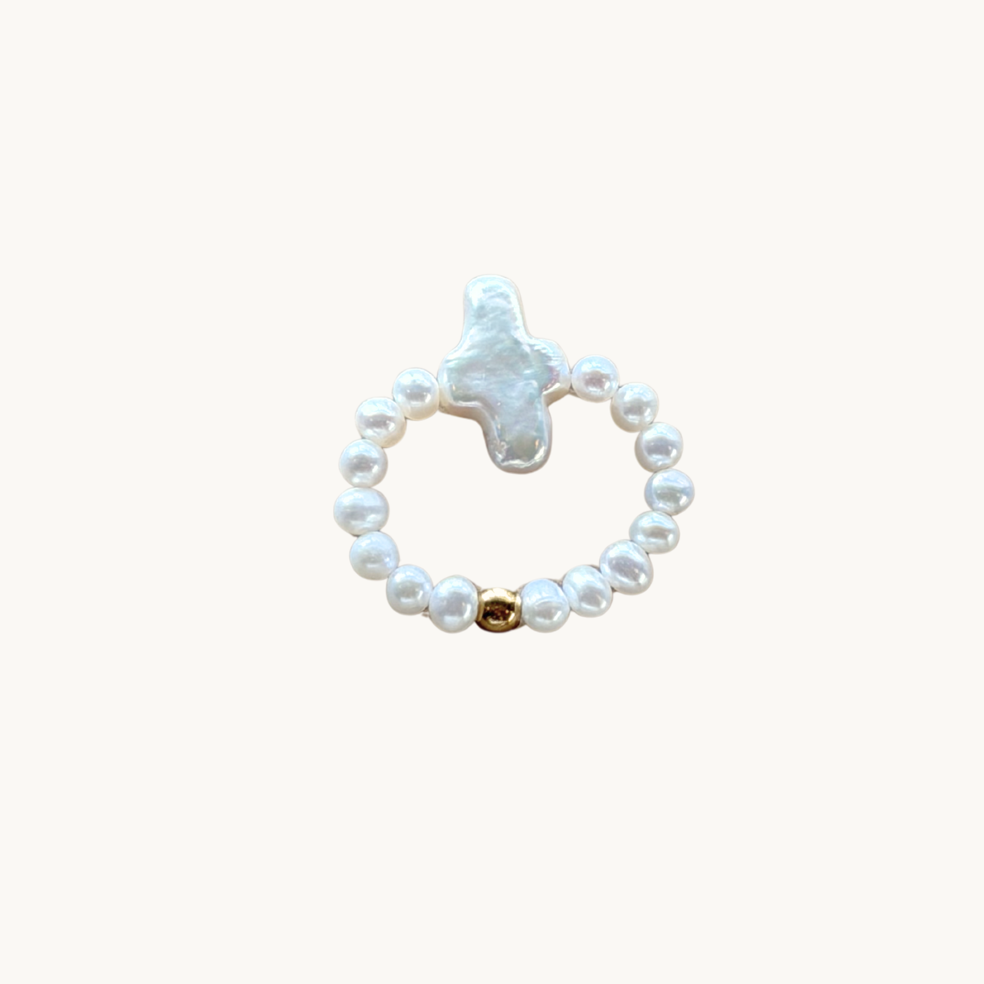 A stylish ring featuring a baroque pearl cross flanked by smaller round pearls with a single gold bead. Elegant and reflective tone.