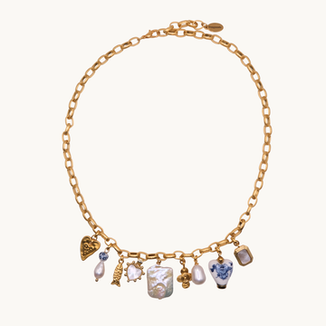 A gold chain necklace with multiple dangling charms, including a blue and white patterned vase, a white pearl, a gold heart, and other small decorative charms, displayed on a clean off-white background.