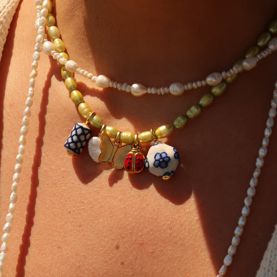 Close-up of a person wearing multiple necklaces with colorful beads on a beige background