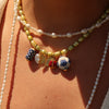 Close-up of a person wearing multiple necklaces with colorful beads on a beige background