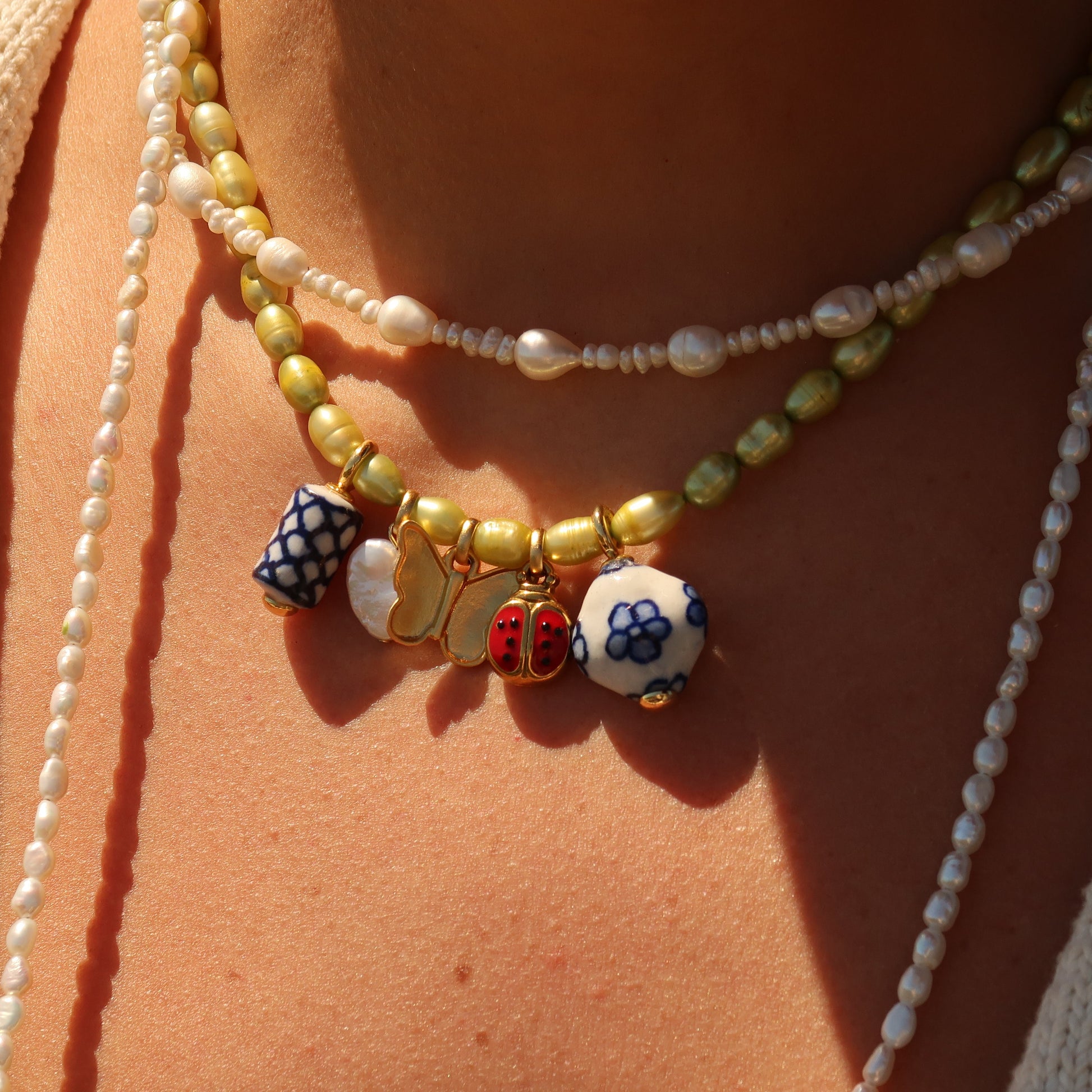 Close-up of a person wearing multiple necklaces with colorful beads on a beige background