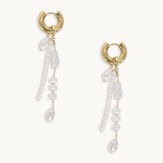 Gold hoop earrings with dangling pearl strings and irregular pearl clusters. The design is elegant and delicate, conveying a sense of luxury and sophistication.