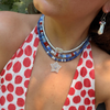 Person wearing a red and white polka dot top with a colorful beaded necklace and earrings.