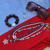 Jewelry including a bracelet, necklace, and earrings on a red and blue striped fabric background.