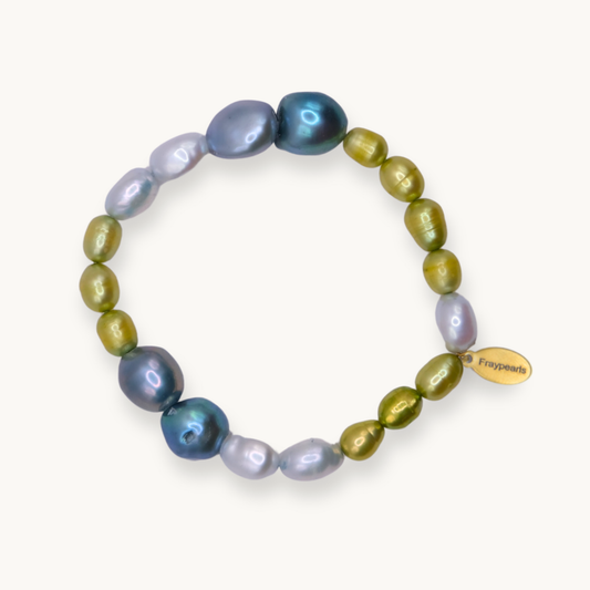 A beaded stretch bracelet featuring a mix of iridescent baroque pearls in blue, purple, and olive green, with a small gold tag on the side.