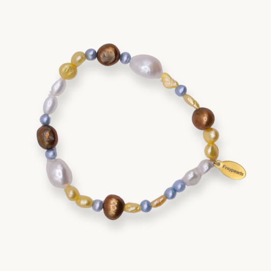 A beaded stretch bracelet featuring a mix of baroque pearls in white, lavender, and brown, small blue beads, translucent yellow beads, and a gold-tone brand tag that reads 'Freyrements'.