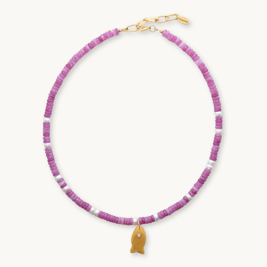 Necklace with pink beads and a gold fish charm on a white background
