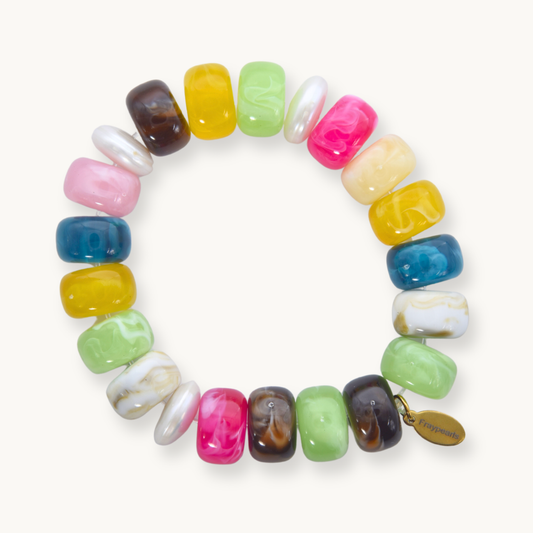 A colorful beaded bracelet arranged in a circular shape, featuring vibrant pink, yellow, blue, green, pearl, and brown beads. A small gold tag is attached.