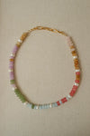 Necklace with multicolored beads and pearls on a beige fabric background