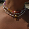 Close-up of a person wearing multiple necklaces with shell and starfish charms.