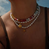 Close-up of a person wearing a necklace with starfish charm against a blurred outdoor background