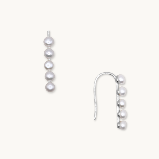 Silver earrings featuring a vertical row of five round white pearls on a hook design, set against a plain white background. Elegant and classy.