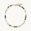Multicolored pearl necklace with brown, blue, yellow, and white pearls with a gold clasp on a white background