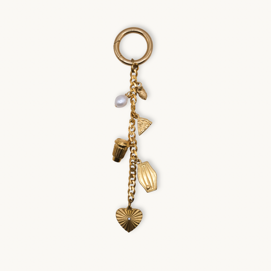 Gold charm bracelet with various charms on a white background
