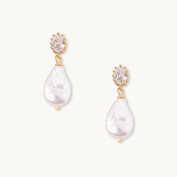 Gold earrings with teardrop-shaped white pearls hanging from oval, faceted stones. The design is elegant and sophisticated on a plain background.