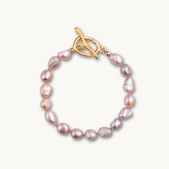 Elegant bracelet with irregular pink pearls linked by a gold toggle clasp. The pearls' lustrous sheen adds a touch of sophistication.