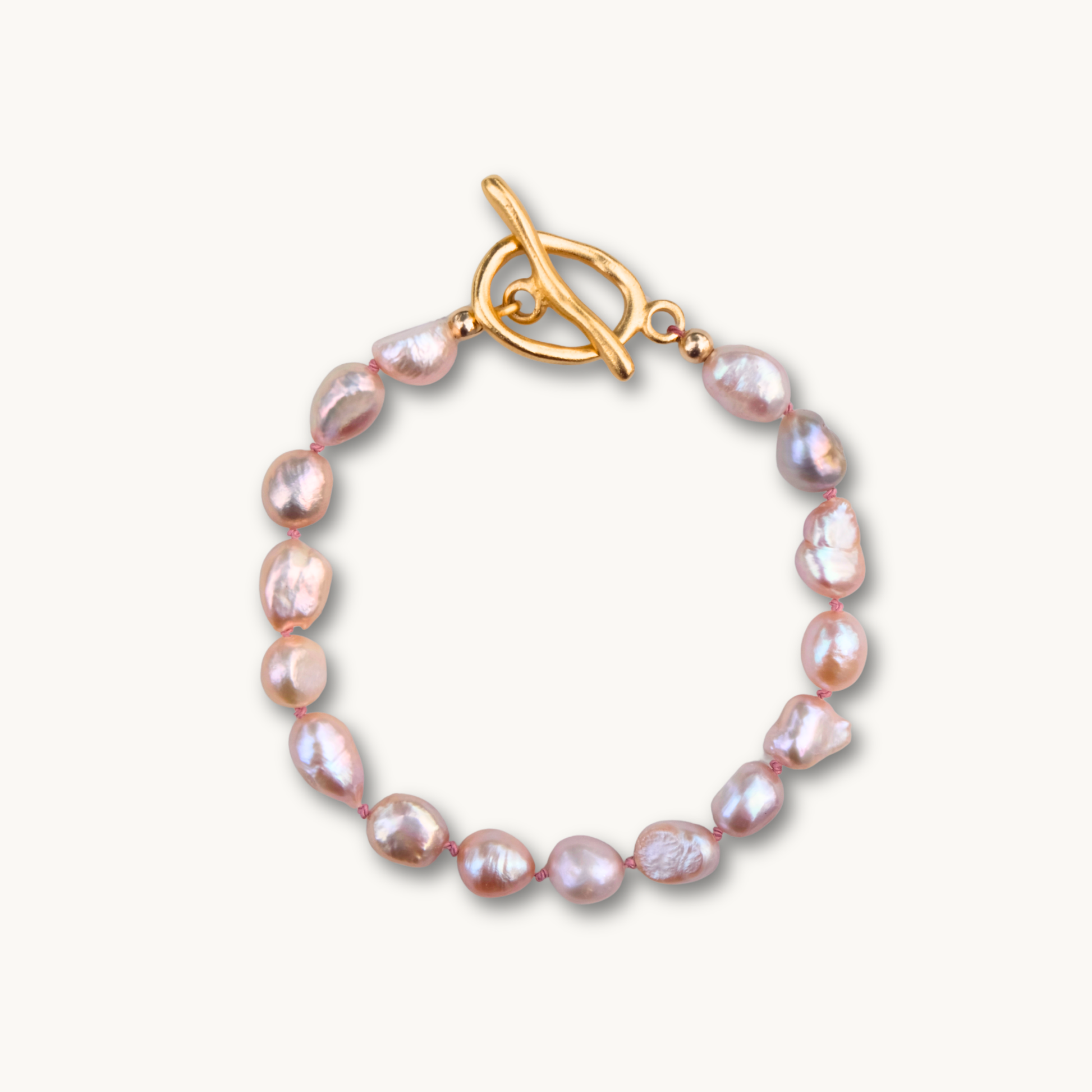 Elegant bracelet with irregular pink pearls linked by a gold toggle clasp. The pearls' lustrous sheen adds a touch of sophistication.