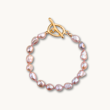 Elegant bracelet with irregular pink pearls linked by a gold toggle clasp. The pearls' lustrous sheen adds a touch of sophistication.