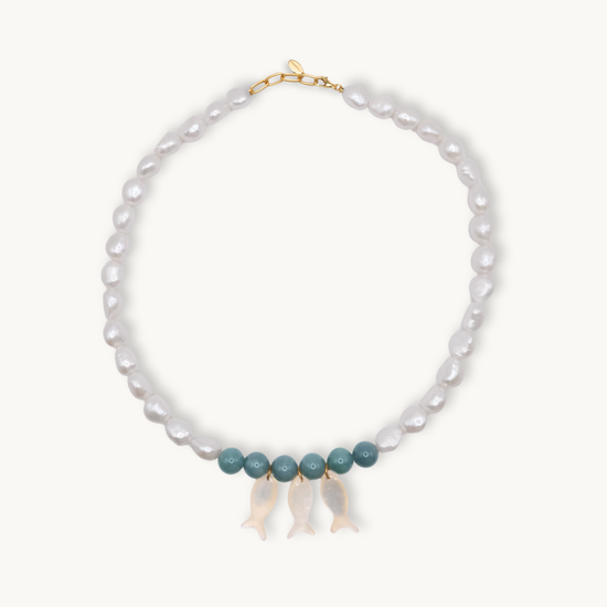 Pearl necklace with jade and gold clasps and pearl fish charms on a white background