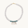 Pearl necklace with jade and gold clasps and pearl fish charms on a white background