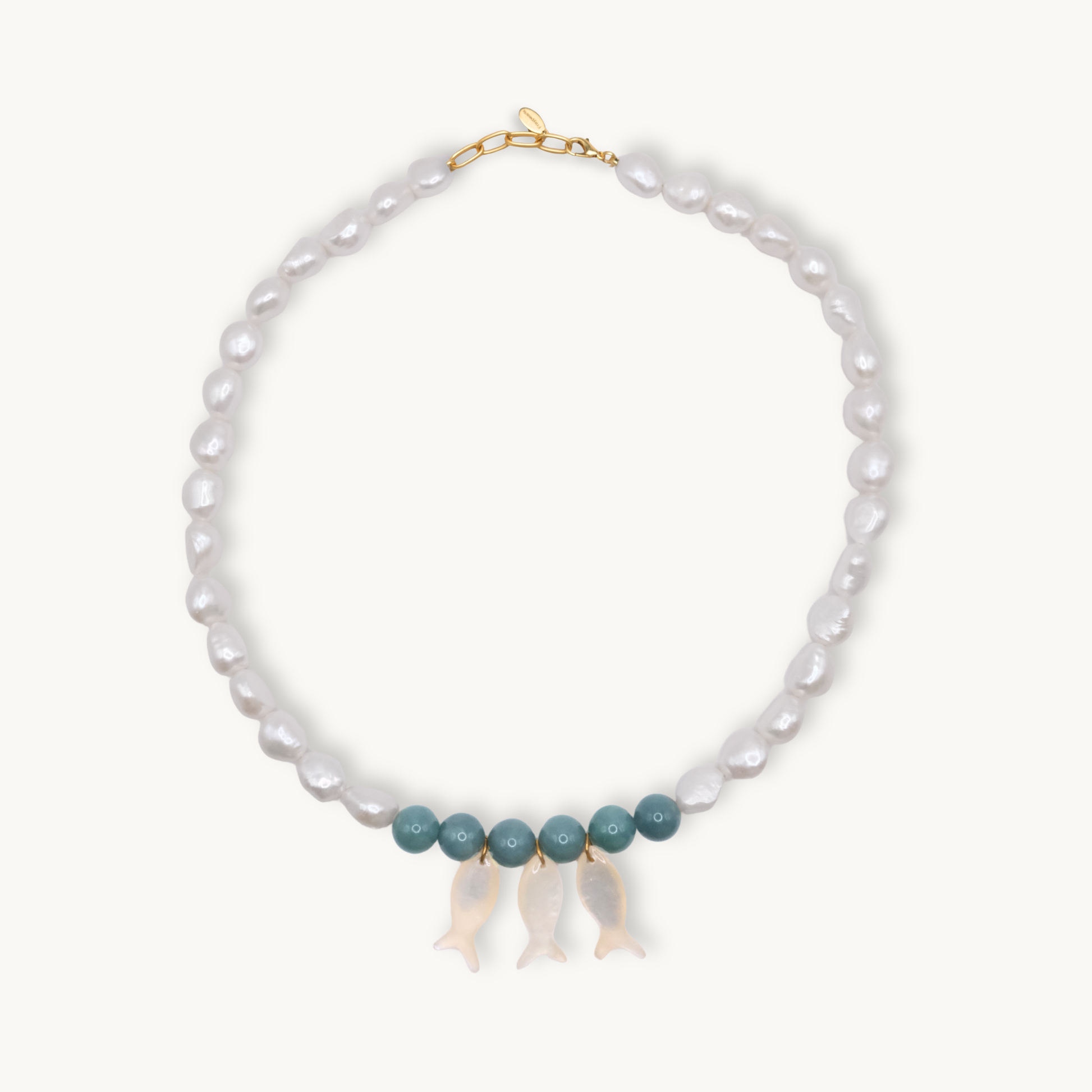 Pearl necklace with jade and gold clasps and pearl fish charms on a white background