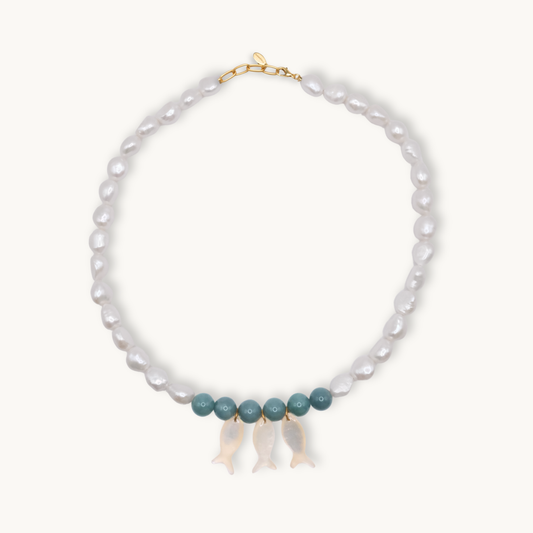 Pearl necklace with jade and gold clasps and pearl fish charms on a white background