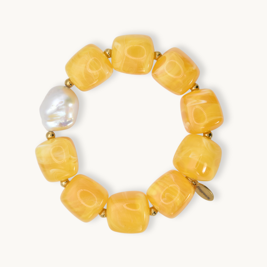 Chunky yellow beaded necklace with pearl and gold closure on white background