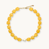 Chunky yellow beaded necklace with pearl and gold closure on white background